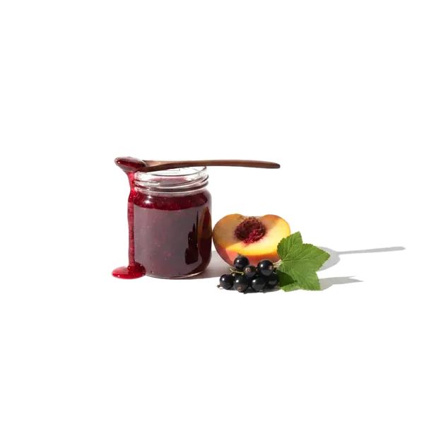 маленькая стеклянная банка с густым тёмно-красным вареньем, рядом половинка персика и веточка чёрной смородины, поперёк банки лежит ложка